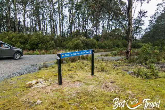 A car on the gravel road and a road sign to the Blue Tier