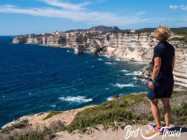 A woman on the coastal path is looking to Bonifacio.