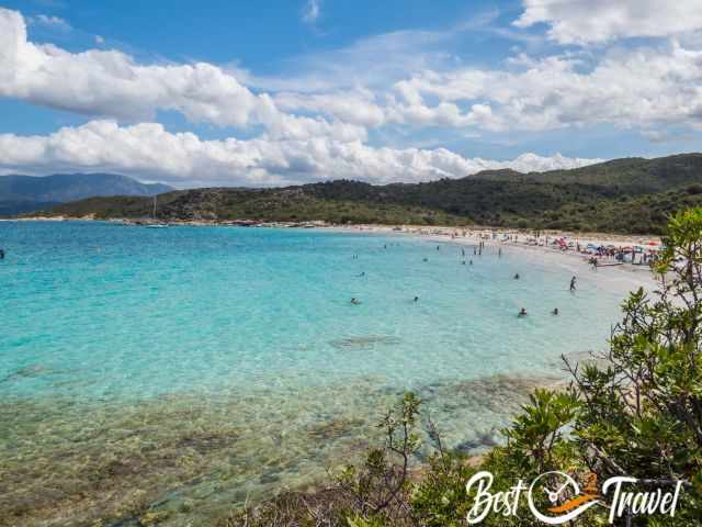 Many visitors in the turquoise sea and on the white beach 