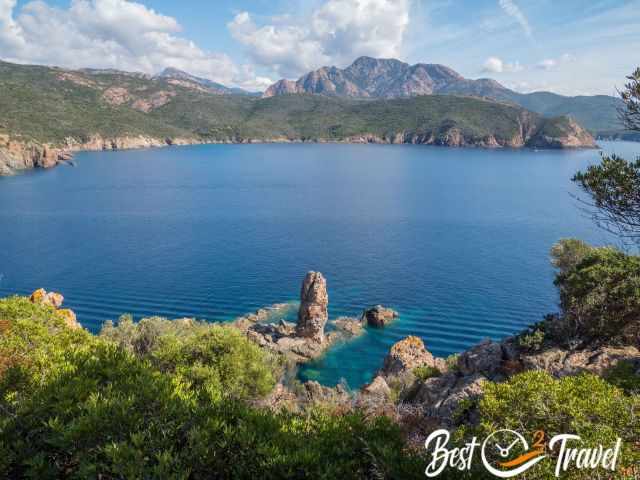 The turquoise sea and a rock formation like a spire. 