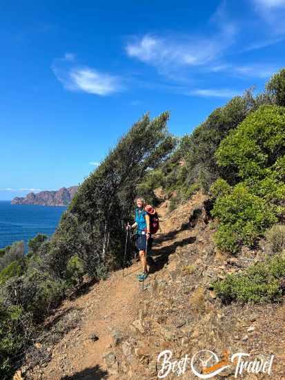 A hiker with hiking poles on the exposed trail.