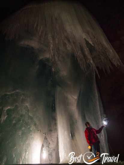 The guid in front of a huge blue ice formation.