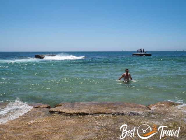 A man swimming in a natural sea water pool.