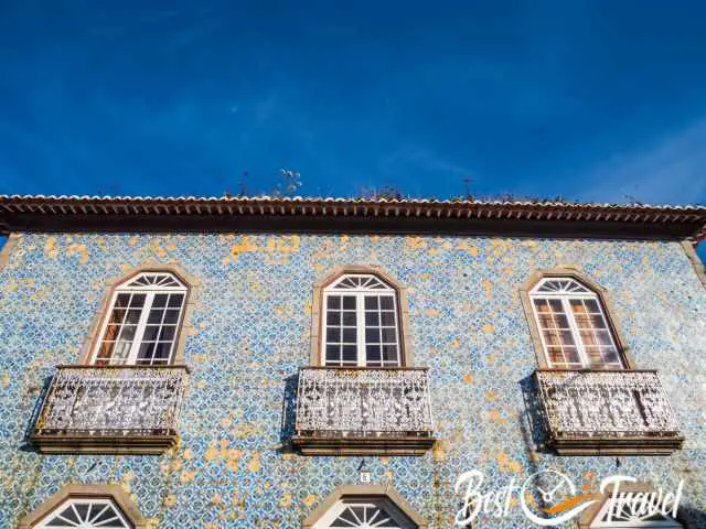 An old building covered with tiles and flowers on the roof.