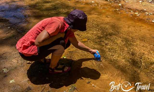 A hiker at a creek putting in a scarf