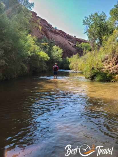 A hiker wading through the Escalante River to Neon Canyon