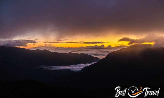 The black shimmerning mountains and the sunrise shimmering through and above the clouds