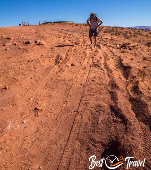 A deep hole in the red sand and a hiker behind