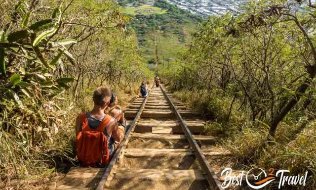 Two hikers resting on side of the railway ties