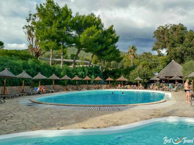 Pool und Whirlpool mit Gästen auf Sonnenliegen.