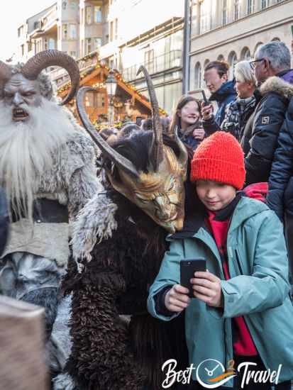 A boy is taking a selfie with a Krampus