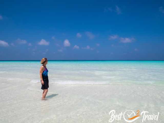 A woman on with her feet in the crystal clear sea.