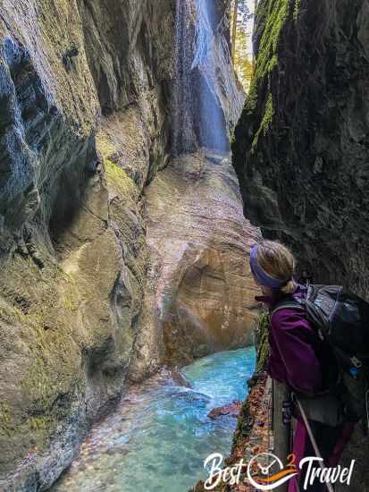 Eine Besucherin die den Wasserfall in der Klamm bewundert.