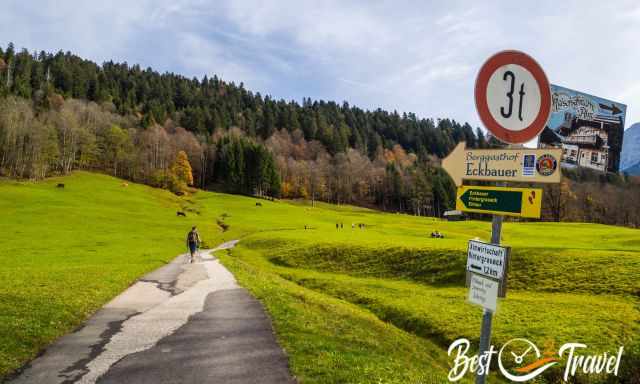 Ein Wanderer auf einem asphaltiertem Weg bergauf.