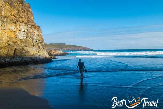 A visitor walking barefoot along the secluded beach.