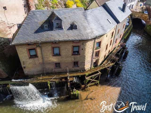 The mill and houses next to the waterfall and river.