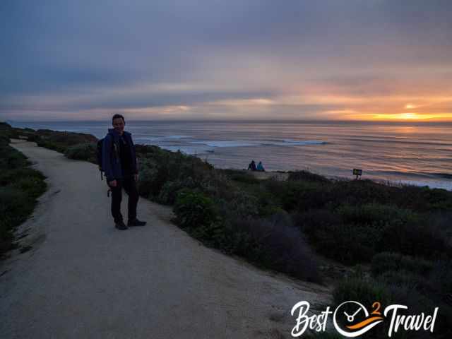 A visitor on the cliff top with the sunset to the right