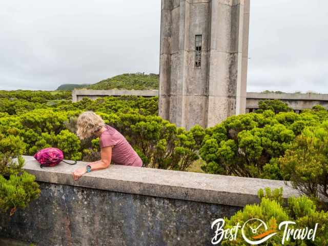 A woman climbs a wall next to the lighthouse.