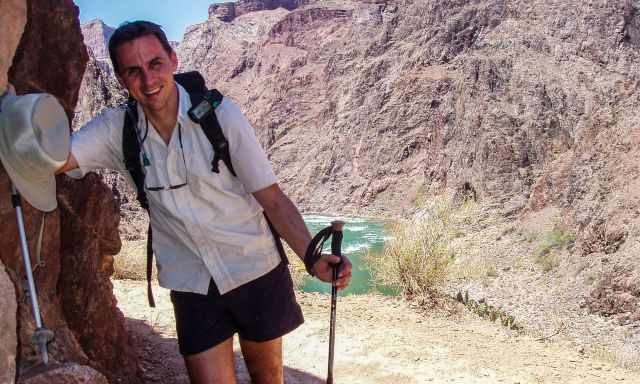 A hiker at the Colorado River in the shade