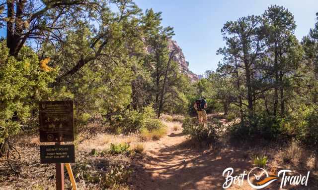 A hiker on the trail where a sign indicates that a permit is required.