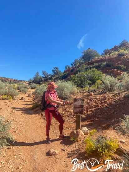 A female hiker pointing to an information sign.