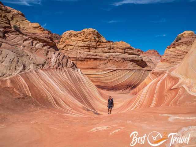 A hiker in the Wave sandstone formation in red and orange