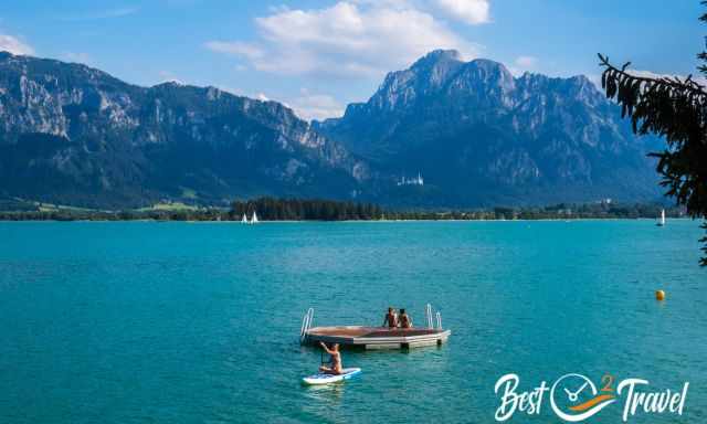 A stand up paddler and swimmers in Lake Forggensee 