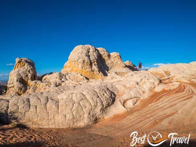 A hiker on top of a pocket next to a swirled rock formation.